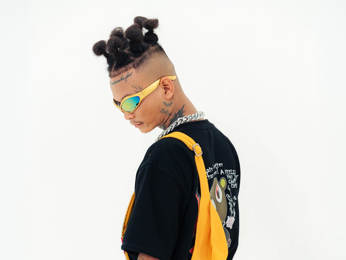 ST MAN standing in yellow overalls and a dark tee