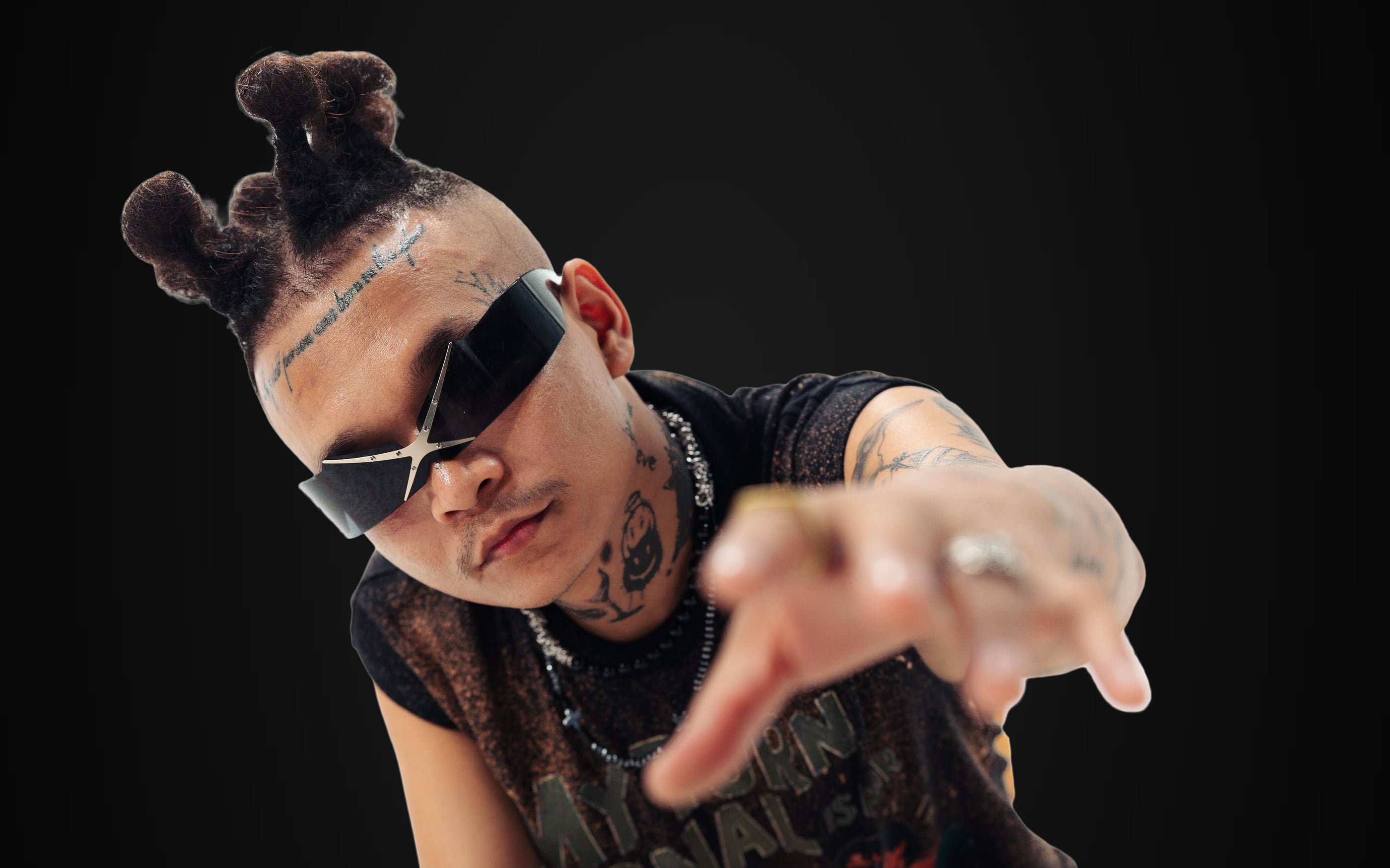 ST MAN crouched forward, pointing straight down the lens in star-shaped shades and a black mesh tee